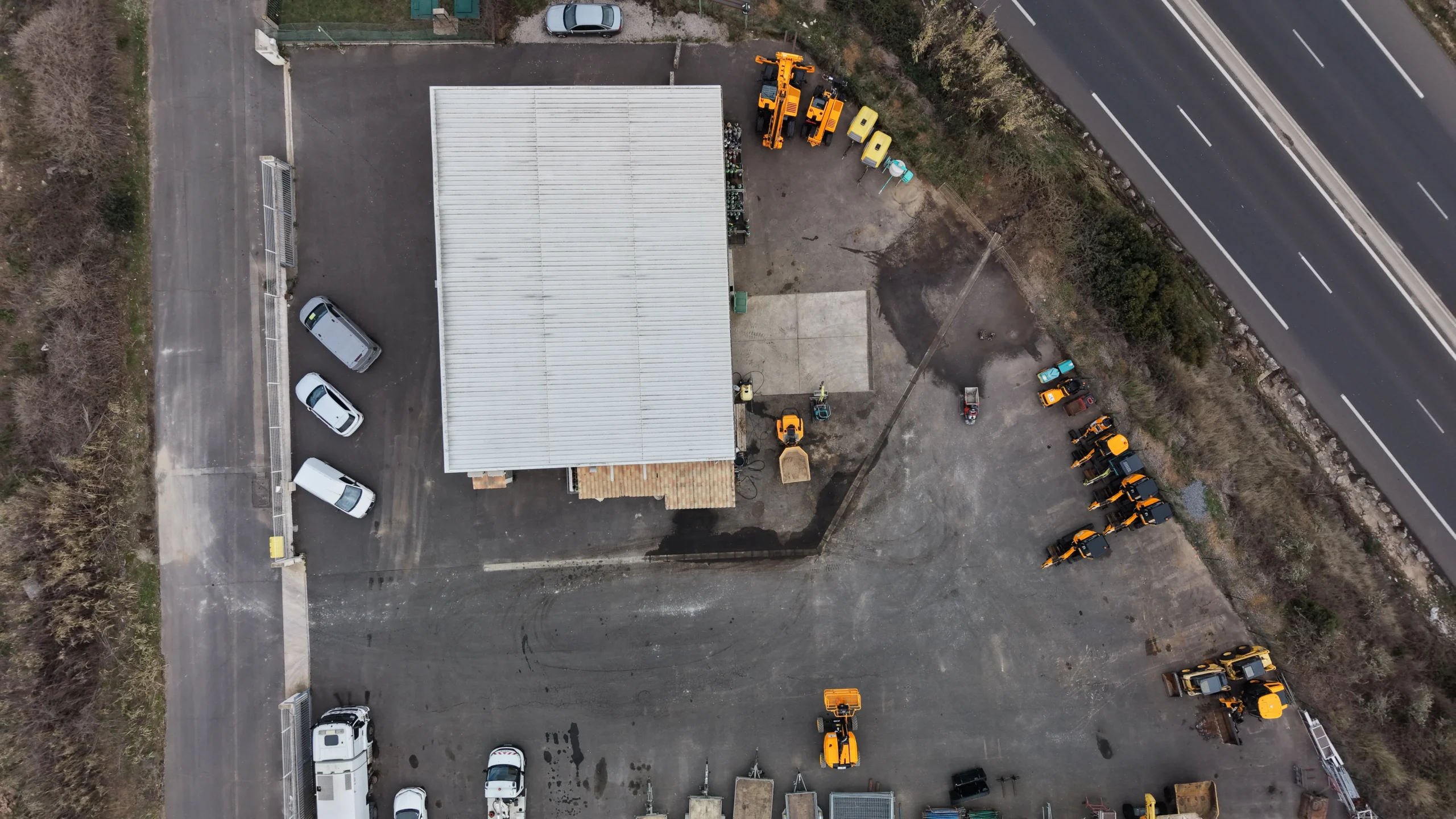 Vue aérienne du dépôt BLS de location de matériel de chantier avec plusieurs engins stationnés.